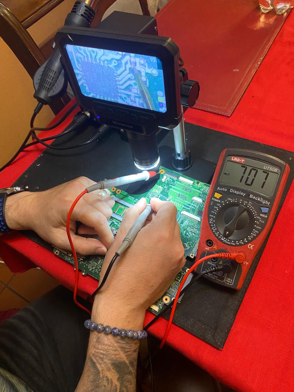 Mediciones con multímetro y microscopio sobre placa electrónica
